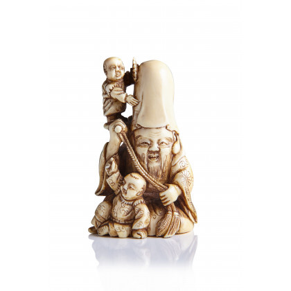 An ivory netsuke of Fukurokuju, the god of longevity, seated with two karako, one of whom stands at his shoulder,...