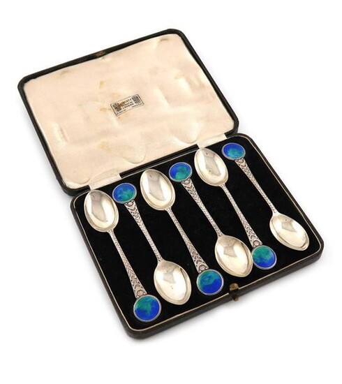 By W. H. Haseler for Liberty, a set of six silver and enamel teaspoons, Birmingham 1914, the tapering stems with chased decoration and with blue / green enamel circular finials, in a fitted case, the inside of the cover with ~Liberty Regent Street...