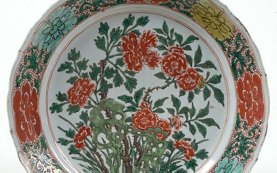 Grand plat chantourné en porcelaine polychrome de Chine à décor floral. Marque en bleu sous couverte à six caractères. Epoque: vers 1700, période Kangxi. (Eclats et fêles). Diam.:+/-35,3cm.