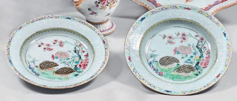 Pair of china soup plates. Qianlong, 18th century. Decorated with enamels of the Rose Family, in the centre quails in a landscape with flowering rocks in a medallion formed by a circle and a braid of ironwork, the wing with a bianco sopra bianco...