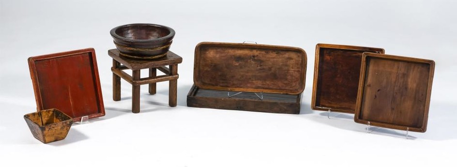 SEVEN CHINESE WOODEN VESSELS AND A SMALL FOOTSTOOL Vessels include five trays, lengths from 13" to 22", a square bowl, height 4", an...