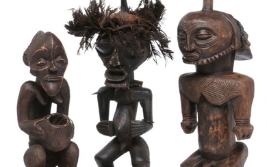 Three ancestor figures of carved patinated wood, one mounted with feathers and horn. Songye and Luba style. H. 49–67 cm. (3)