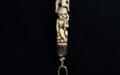Two-toothed fork in gilt red, the ferrule decorated with filigree silver rinceaux, the ivory handle carved with three overlapping putti holding fruits and a horn of plenty.