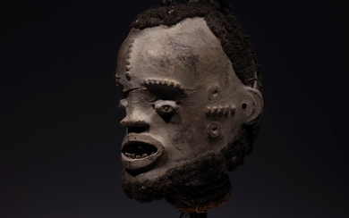Une tête sculptée au front et aux tempes scarifiés en relief, très ancien masque cimier,...