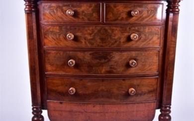 A large flame mahogany bow-front chest with two short over three long drawers, flanked by faceted column supports on raised,...