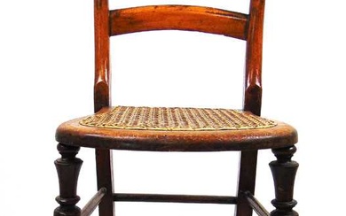 A 19th century beech correction chair with caned seat and...