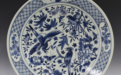 A Chinese blue and white porcelain circular dish, late 19th century, painted with magpies amidst peo
