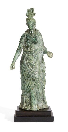 A Hellenistic bronze statue of the Isis Fortuna, 1st Century B.C., the goddess stands with her weight on her right leg, wearing a chiton and himation belted below her breasts and falling in soft folds to the ground, her extended left hand would...