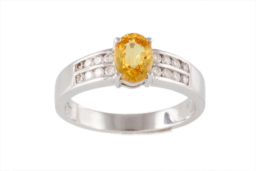 A SAPPHIRE AND DIAMOND RING, with central oval cut yellow sa...