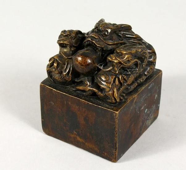 A SQUARE BRONZE SEAL, mounted with dragons. 3ins wide.