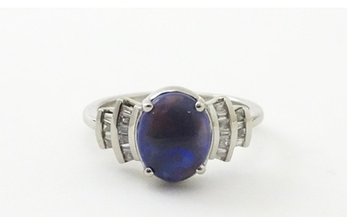 A platinum ring set with central black opal cabochon flanked...