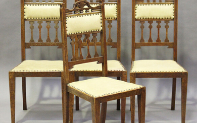 A set of four Edwardian Arts and Crafts oak framed dining chairs with pierced top rails and stylized