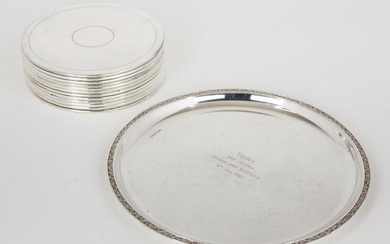 A set of twelve silver plated place mats, of circular form, with ringed decoration and felt undersides, 19cm dia., together with a round silver plated tray with presentation engraving to centre, 29.9cm dia. (13)