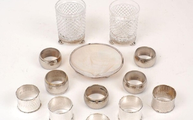A silver mounted mother of pearl shell dish, raised on three ball feet, stamped 925, together with a pair of cut glass tumblers on white metal mounts, and ten various silver plated napkin rings, including a set of five rings of hammered design with...