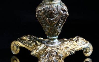Candleholder in cast and gilded bronze, resting on a tripod base with a scrolling base decorated with heads of bearded mascarons, the taper of baluster form with decoration of mascarons, drapes and fleurons.