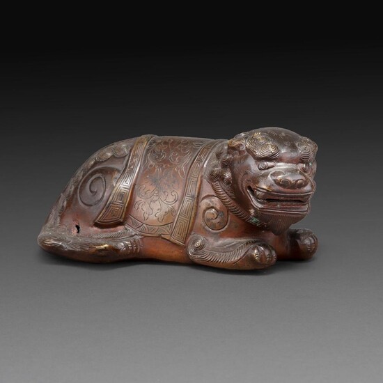 SUJET en bronze, représentant un lion couché, ciselé de motifs floraux. (Petit accident). Chine, XIXe siècle. A BRONZE FIG...