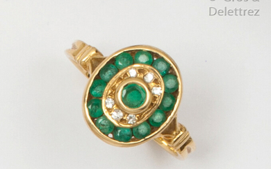 Yellow gold ring, set with an emerald in a double surround of brilliant-cut diamonds and emerald in a rail-set. Finger size: 53. P. Rough: 3.9g.