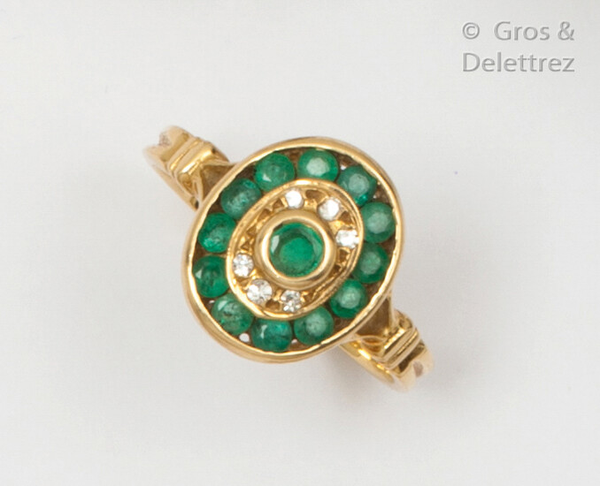 Yellow gold ring, set with an emerald in a double surround of brilliant-cut diamonds and emerald in a rail-set. Finger size: 53. P. Rough: 3.9g.