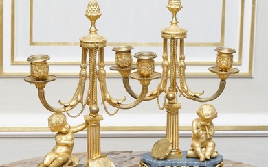 Paire de candélabres de style Louis XVI, fin XIXe s., en bronze ciselé et doré, figurant des putto musiciens accoudés à un fût cannel