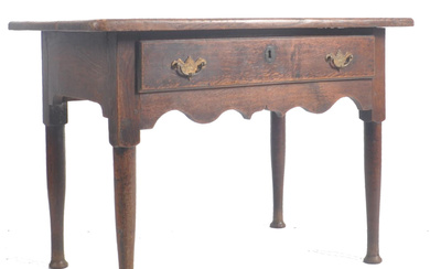 A George III 18th century oak lowboy side low table. The table having a chamfered edge over a full length central drawer with brass escutcheons & handles. Fitted shaped frieze below. Raised on tapering supports with pad feet. Measures 68cm x 95cm x 60cm.