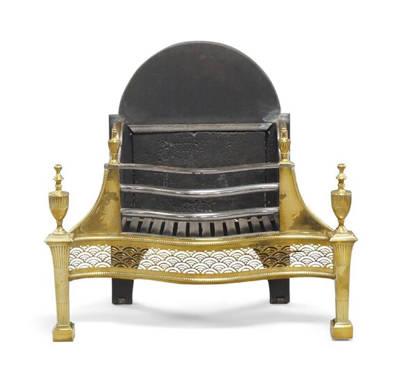 A George III style brass and cast iron fire grate, the serpentine front with floral engravings and pierced apron and urn shape finials, raised on reeded supports and spade feet, 81cm high, 85cm wide, 39cm deep