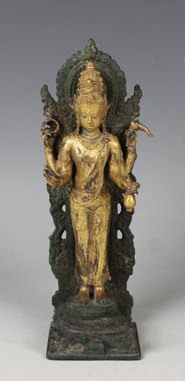 A Tibetan gilt and green patinated bronze figure of a crowned Buddha, 17th century, the gilt four-ar