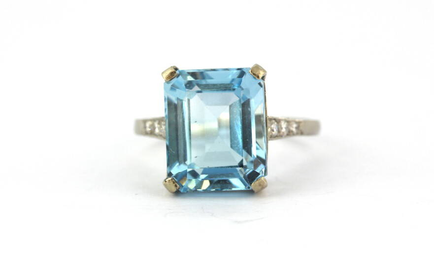 A white metal (tested high carat gold) ring set with an emerald cut aquamarine and brilliant cut diamond set shoulders, approx. 8ct aquamari