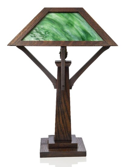 An Arts & Crafts 'Mission Style' oak and marbled glass table lamp, probably American, c.1920, Stained oak frame supporting four marbled green and white glass panels, united to the central column by angled supports, on a stepped, square foot, 57 cm...