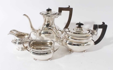 George V silver and silver plated composite four piece tea and coffee set- comprising teapot of compressed baluster form, hinged domed cover, angular ebony handle, raised on four ball feet