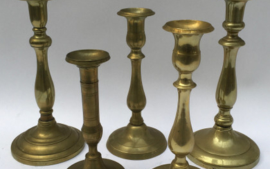 Lotto composto da cinque candelieri in ottone con base circolare. Epoche diverse (h. max cm 25,5) (lievi difetti)