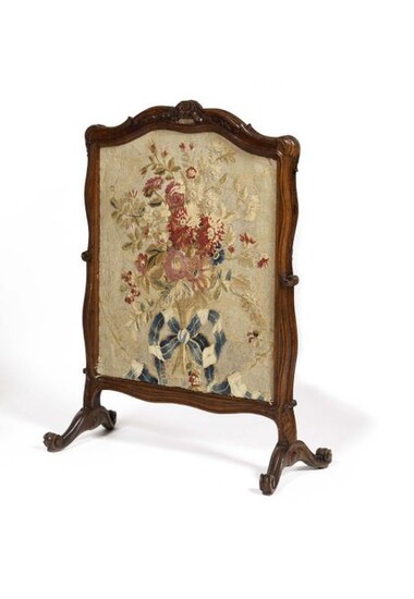 Moulded and carved walnut mantel screen decorated with flowers and foliage, resting on a scrolled base, adorned with a dotted tapestry sliding leaf, inscribed in ink on the reverse: "Cadir bleu" (blue frame). Louis XV period. H : 101 cm, L : 65 cm...