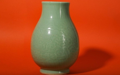 A CHINESE CELADON-GLAZED 'DRAGON' VASE. Qing Dynasty, Guangxu period. With a pear-shaped body rising to a waisted neck and supported on a short spreading foot, incised with a pair of sinuous dragons against foliate ground, a band of ruyi heads to the...