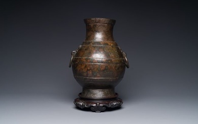A Chinese bronze 'hu' vase with Han-style taotie handles on wooden base, Ming