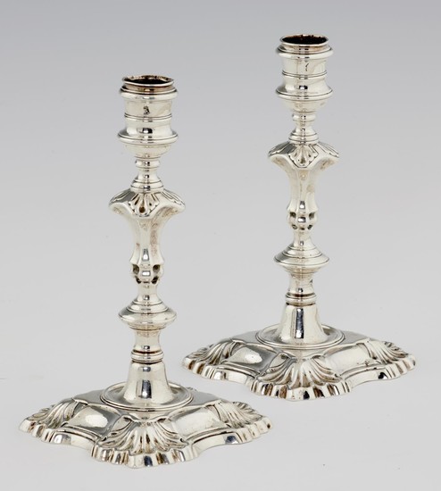 A PAIR OF GEORGE II SILVER CANDLESTICKS on shell cornered f...