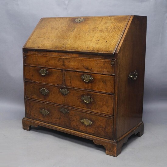 A Queen Anne walnut bureau, circa 1710, the drop flap enclosing fully fitted interior with drawers and leather skiver, above two short and two long oak lined drawers, raised on bracket feet, 106cm high, 96cm wide, 55cm deep Provenance: Property of...