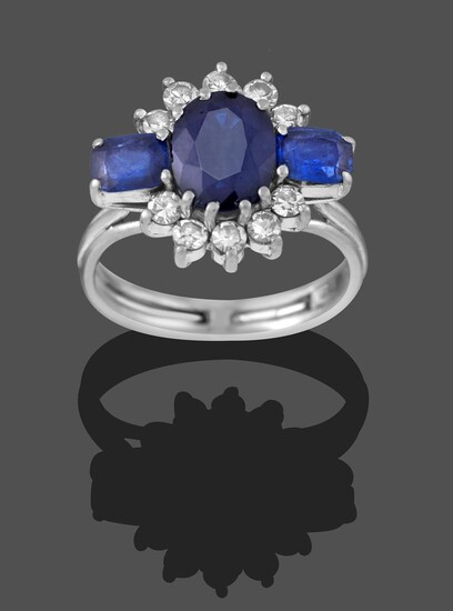 A Sapphire and Diamond Cluster Ring, by Graff, circa 1960, the oval cut sapphire flanked by two...