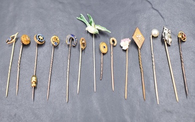 A collection of yellow metal stick pins including an enamel and diamond set horse shoe, a seed pearl