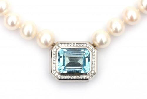 A cultured pearl necklace with a white gold topaz and diamond set clasp. Featuring thirty nine knotted white cultured fresh water pearls with a soft pinkish luster. The 18 carat white gold clasp is featuring an emerald cut blue topaz of ca. 33 ct...