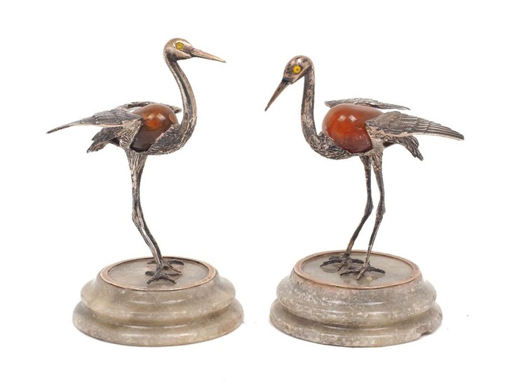 A pair of white metal and hardstone models of storks, both stamped 925, each bird raised on a green hardstone base and modelled in standing pose with raised wings, both designed with polished orange/brown ovoid hardstone body, 11.5 and 12 cm high (2)