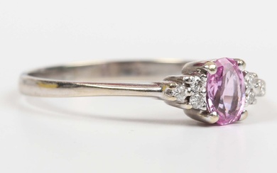 A pink sapphire and diamond ring, claw set with the oval cut pink sapphire between three circular cu