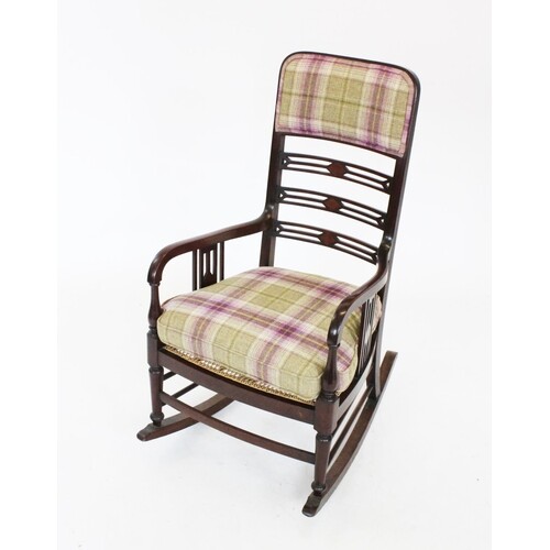 An Edwardian mahogany rocking chair, with a padded back rest...
