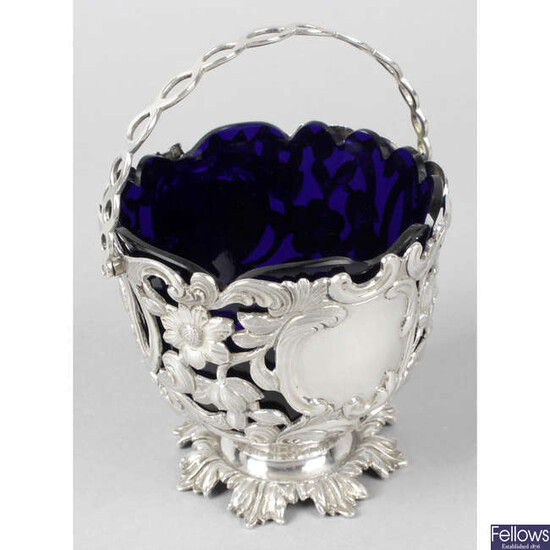 An early Victorian silver pierced and swing-handled sugar basket with blue glass liner.