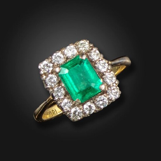 An emerald and diamond cluster ring, the emerald-cut emerald is...