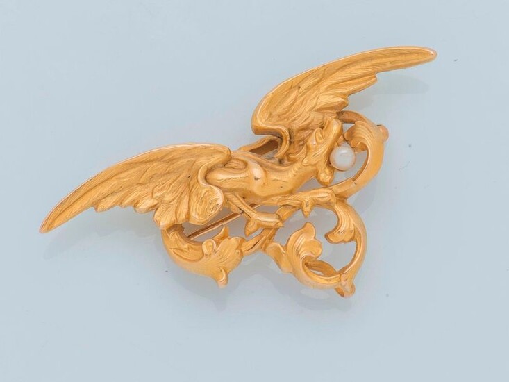 Brooch in 18 karat yellow gold (750 thousandths) stylizing a winged chimera on foliage, holding a pearl in its mouth.