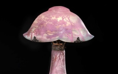 Daum Nancy: A overlaid, etched glass table lamp decorated with wooded lakeland landscape in shades of rose on a amber-yellow and blue base. H. 50 cm.