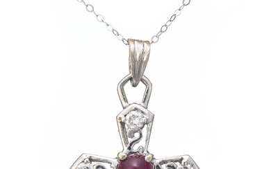 Pendentif or gris en forme de croix serti au centre d'un rubis cabochon rouge, les branches terminées par quatre diamants