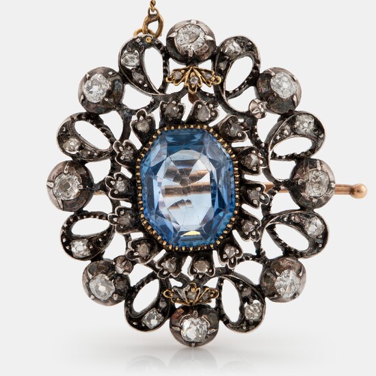 A 14K gold and silver brooch set with a synthetic sapphire and old- and rose-cut diamonds.
