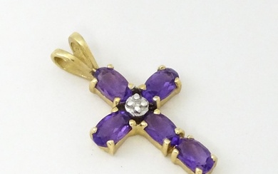 A 9ct gold cross formed pendant set with amethyst and centra...