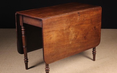 A George IV Mahogany Drop Leaf Dining Table. The rectangular top with rounded corners on four turned