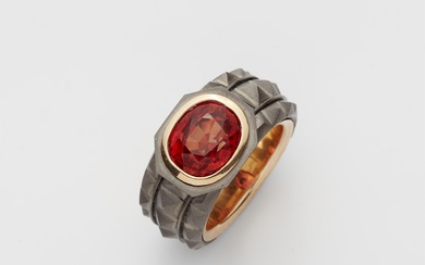 A German 18k gold and forged grey iron band ring with a natural orange coloured sapphire.